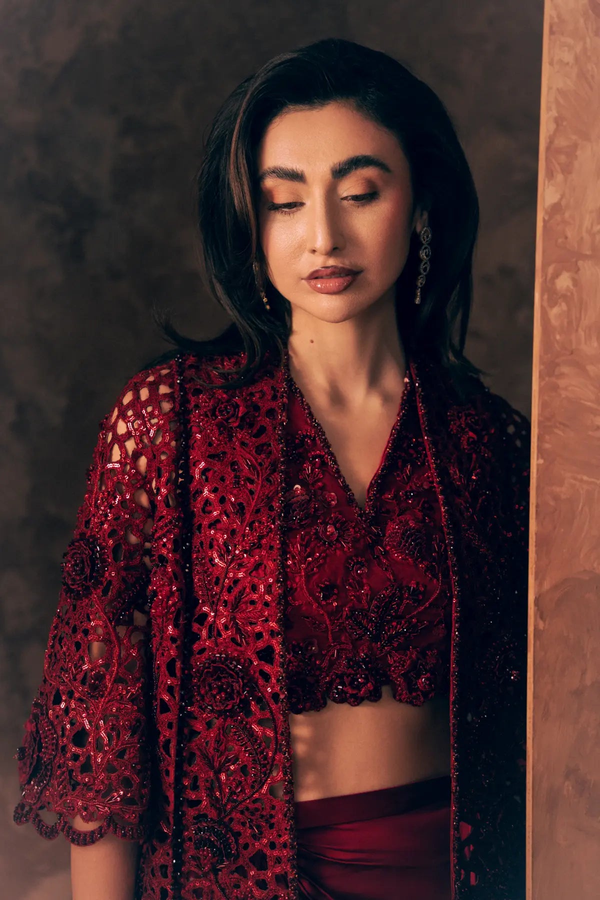 Close-up of Crimson luxury Pakistani clothing with sequin cutwork jacket, rose embroidery, beads and scalloped sleeve hem