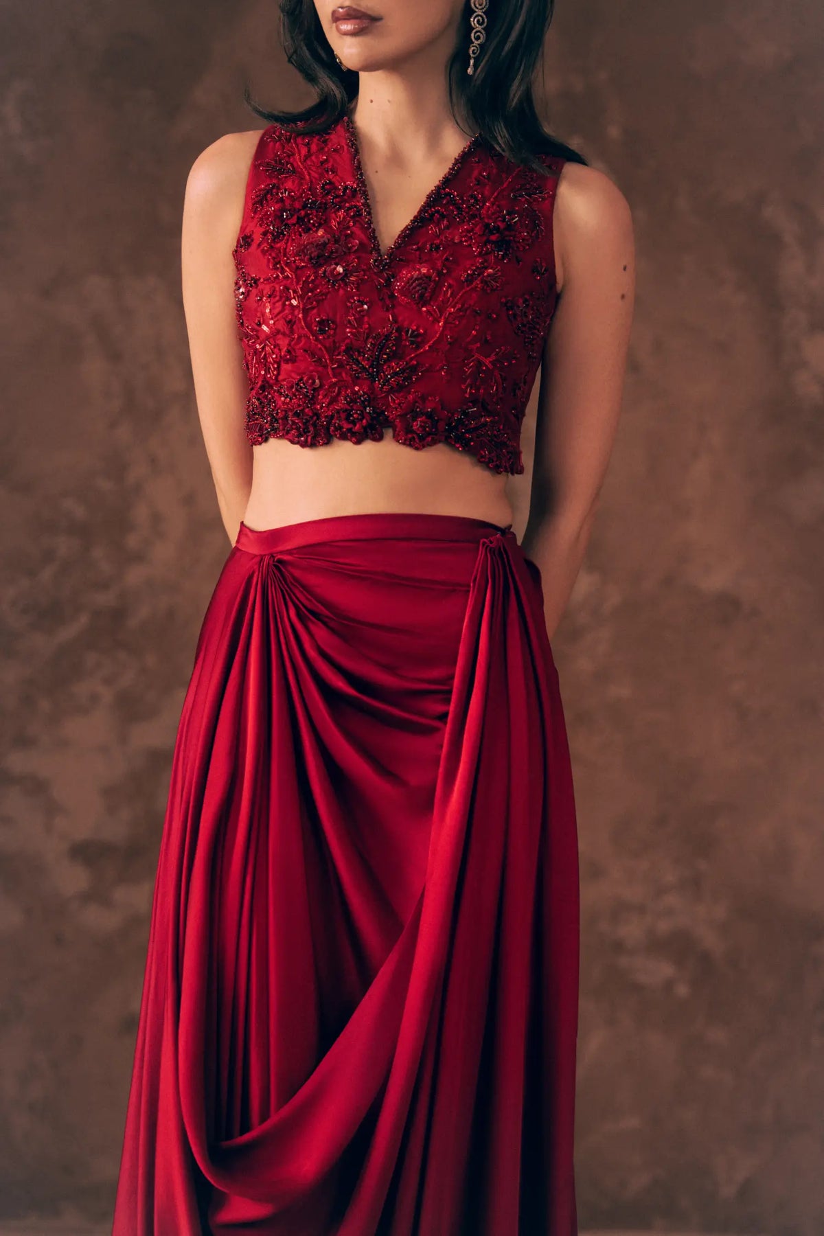 Close-up of Crimson beaded V-neck blouse with scalloped hem and gathered satin silk draped skirt