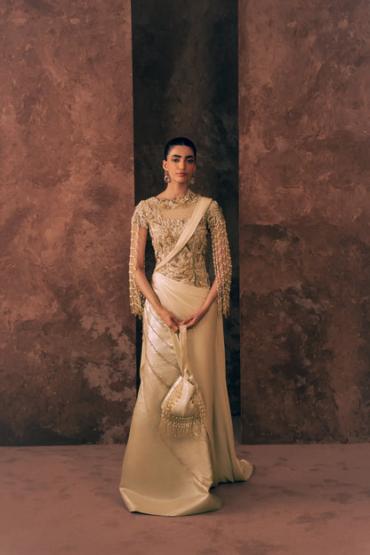 Woman wearing Vestis Pret Pearl Drapes 1 piece Pakistani formal dress with pearl fringe sleeves and beaded diagonal lines on satin silk skirt, styled with a beaded potli bag, front view