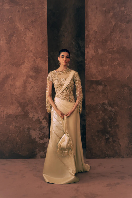 Woman wearing Vestis Pret Pearl Drapes 1 piece Pakistani formal dress with pearl fringe sleeves and beaded diagonal lines on satin silk skirt, styled with a beaded potli bag, front view