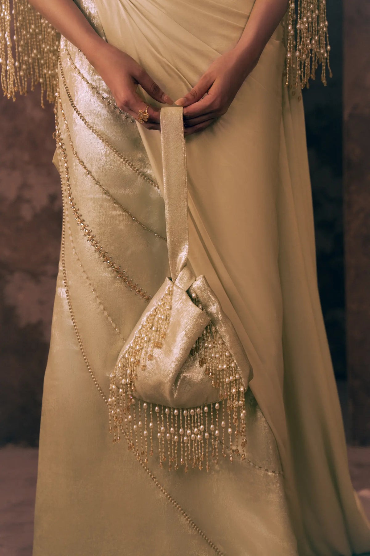 Detail of Pearl Drapes Pakistani party wear dress with diagonal beaded lines on shimmering satin silk skirt, styled with a pearl fringe potli bag